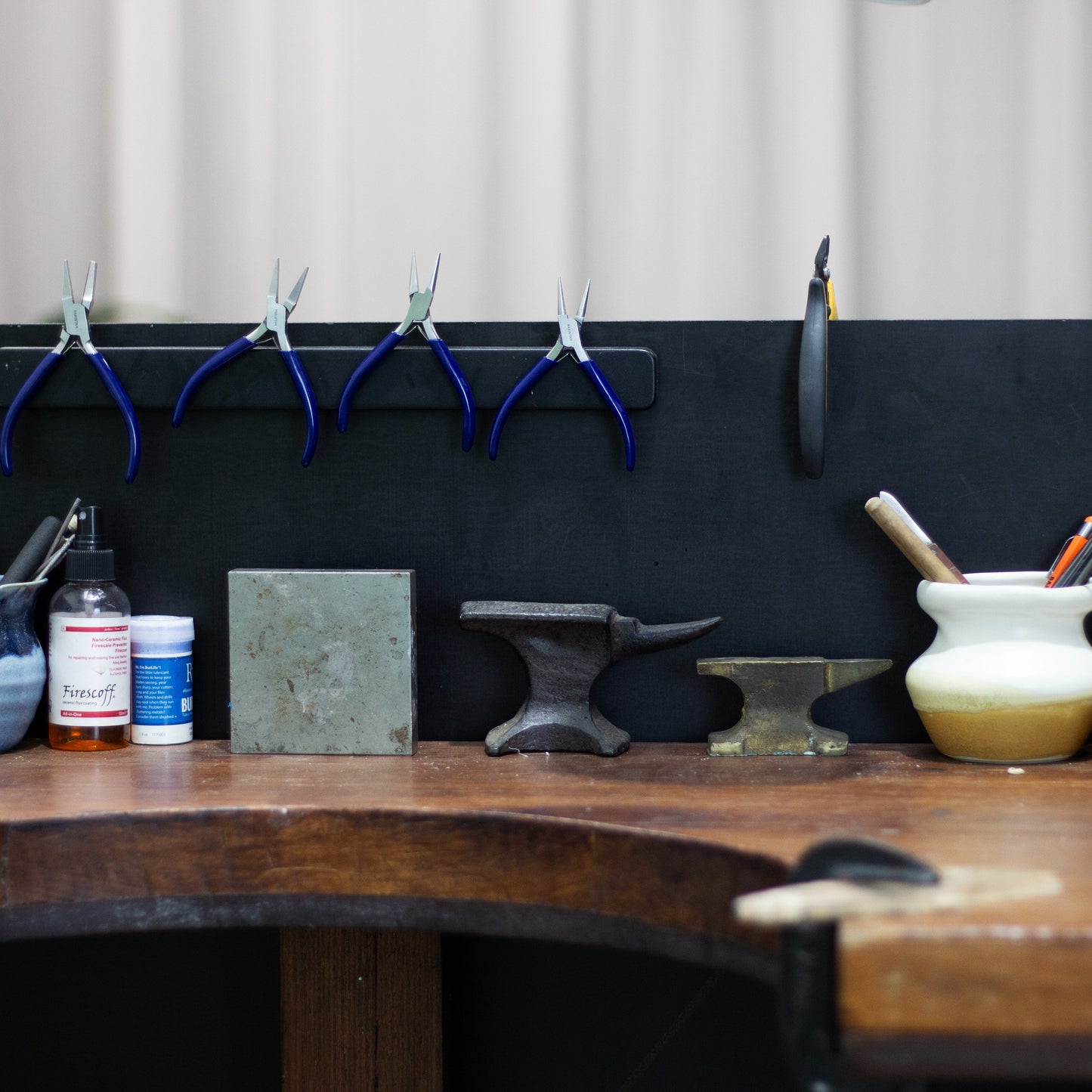 Workbench with various tools and items against a blackboard wall.